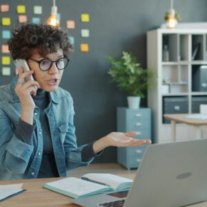 Time wasted Woman talking on phone at desk with laptop